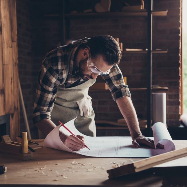 Draft workbench creative profession restoration people person industry concept. Close up photo portrait of smart handsome concentrated workman architect making notes analyzing architecture design plan